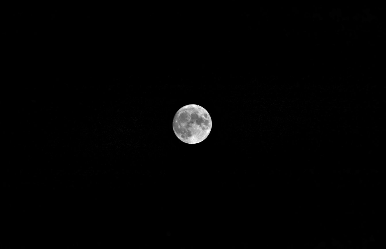 A full moon glows against a deep black night sky.